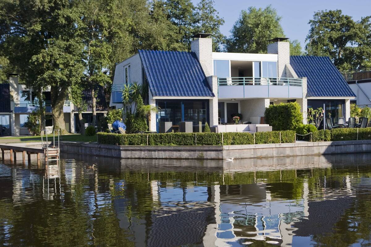 A modern house with a blue roof, a balcony, and a small garden area.