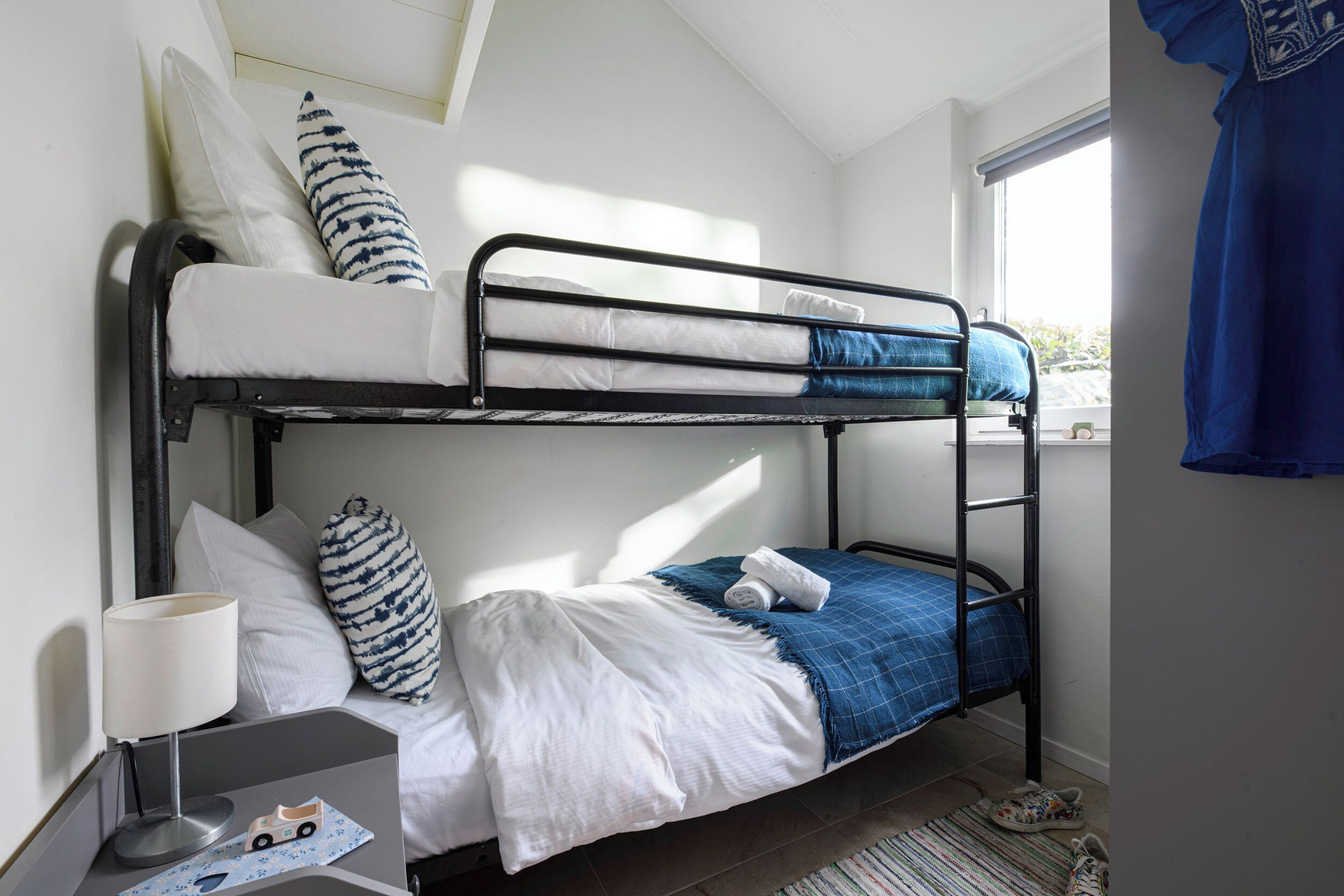Habitación con literas, un escritorio, una lámpara y una ventana con cortinas.