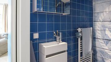 A bathroom with blue tiles, a white sink, a towel rack, and a mirror.