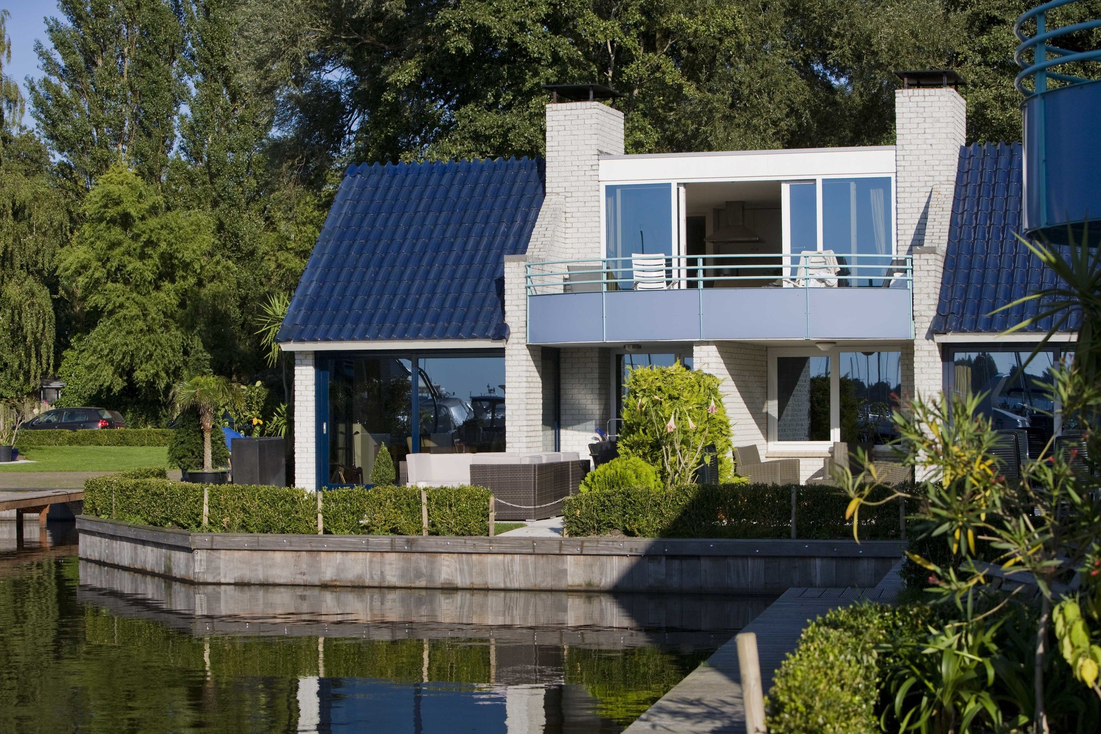 Una casa moderna de dos pisos con balcón, piscina y jardín.