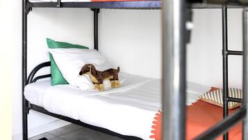 A bunk bed with a plush toy on the lower bunk, a striped rug, and a pair of yellow shoes on the floor.
