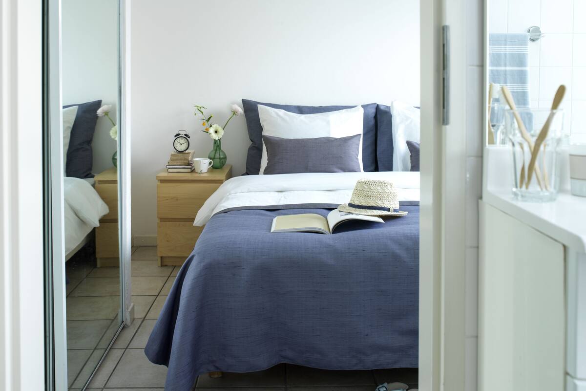 A neatly arranged bedroom with a bed, bedside table, and a nightstand.