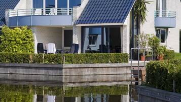 A modern two-story house with a balcony, a swimming pool, and a garden.