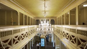Upea aula, jossa on suuri kattokruunu, koristeelliset kaiteet ja myyntiautomaatti.
