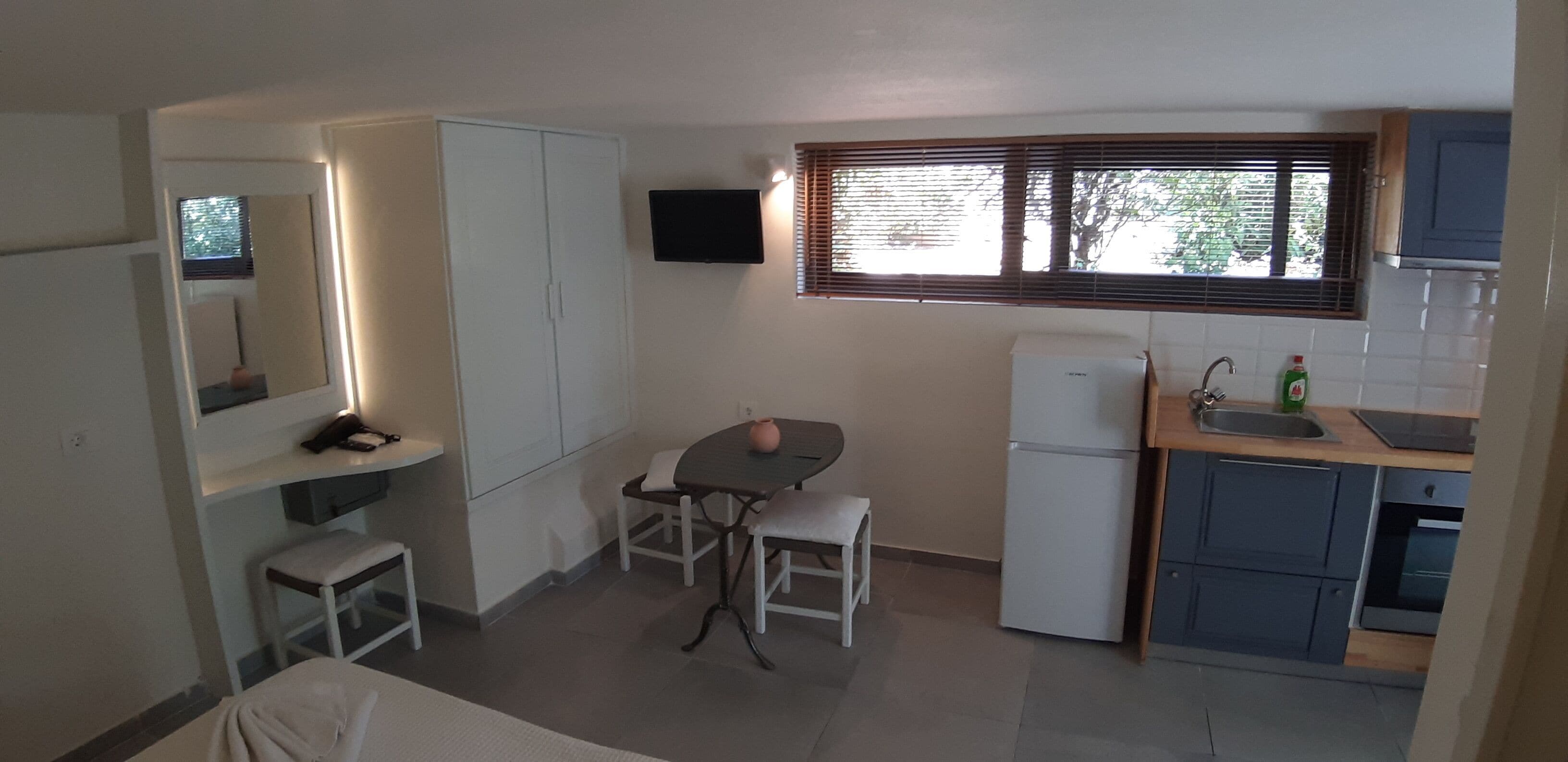 A compact kitchen with a refrigerator, sink, and a small dining area with a table and chairs.