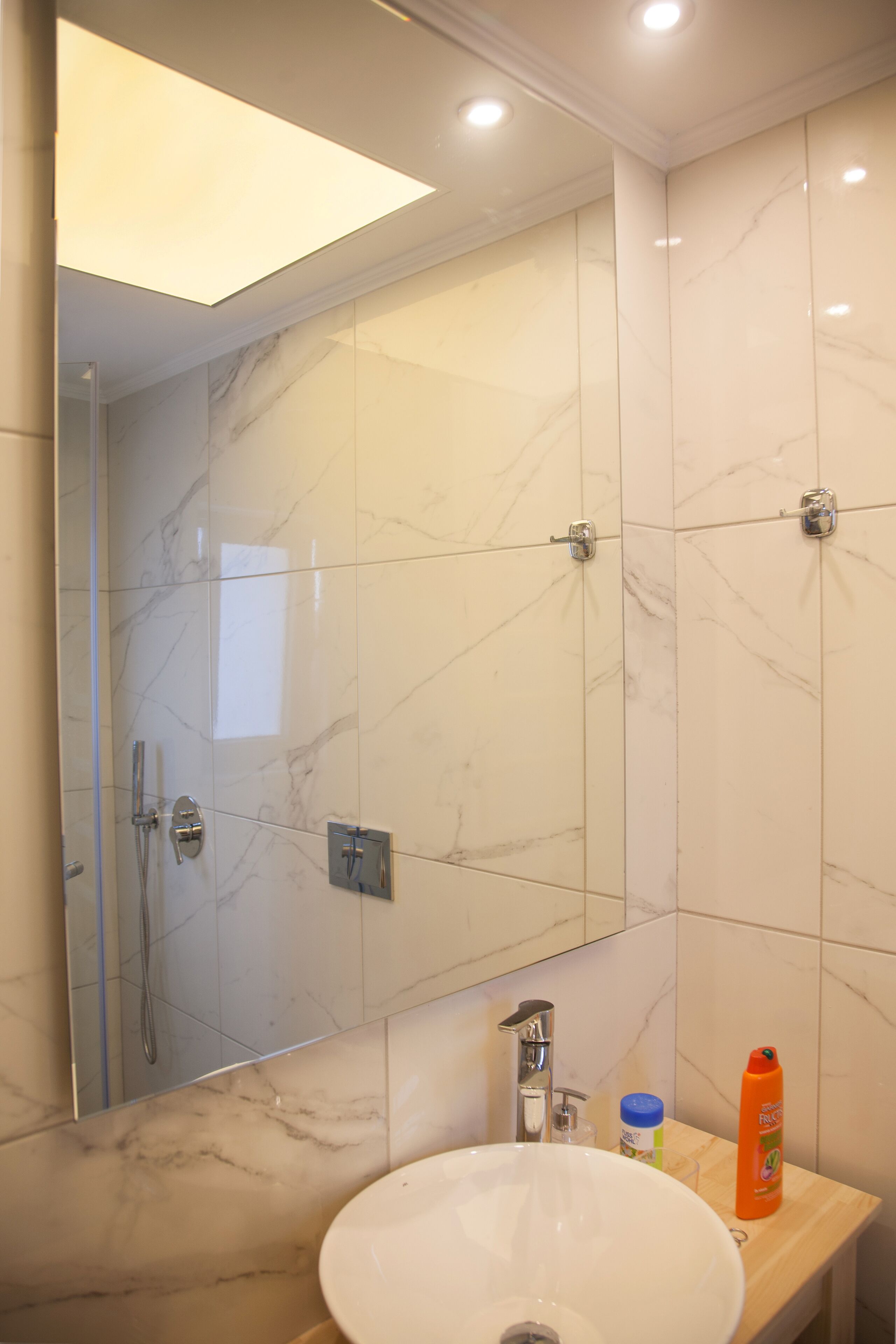 A bathroom with a large mirror, a sink, and a shower.