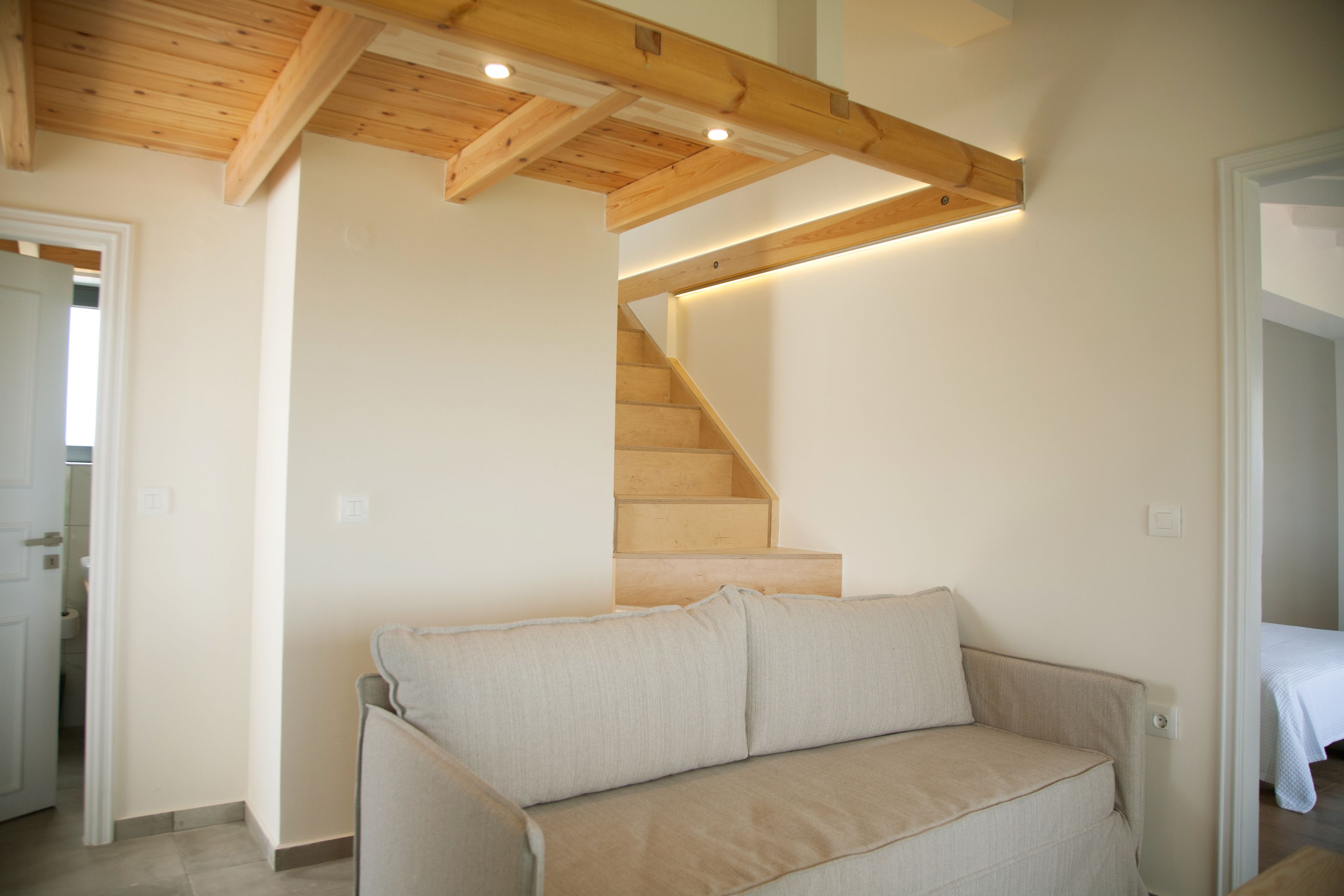 Una escalera con vigas de madera y un sofá beige en un pasillo.