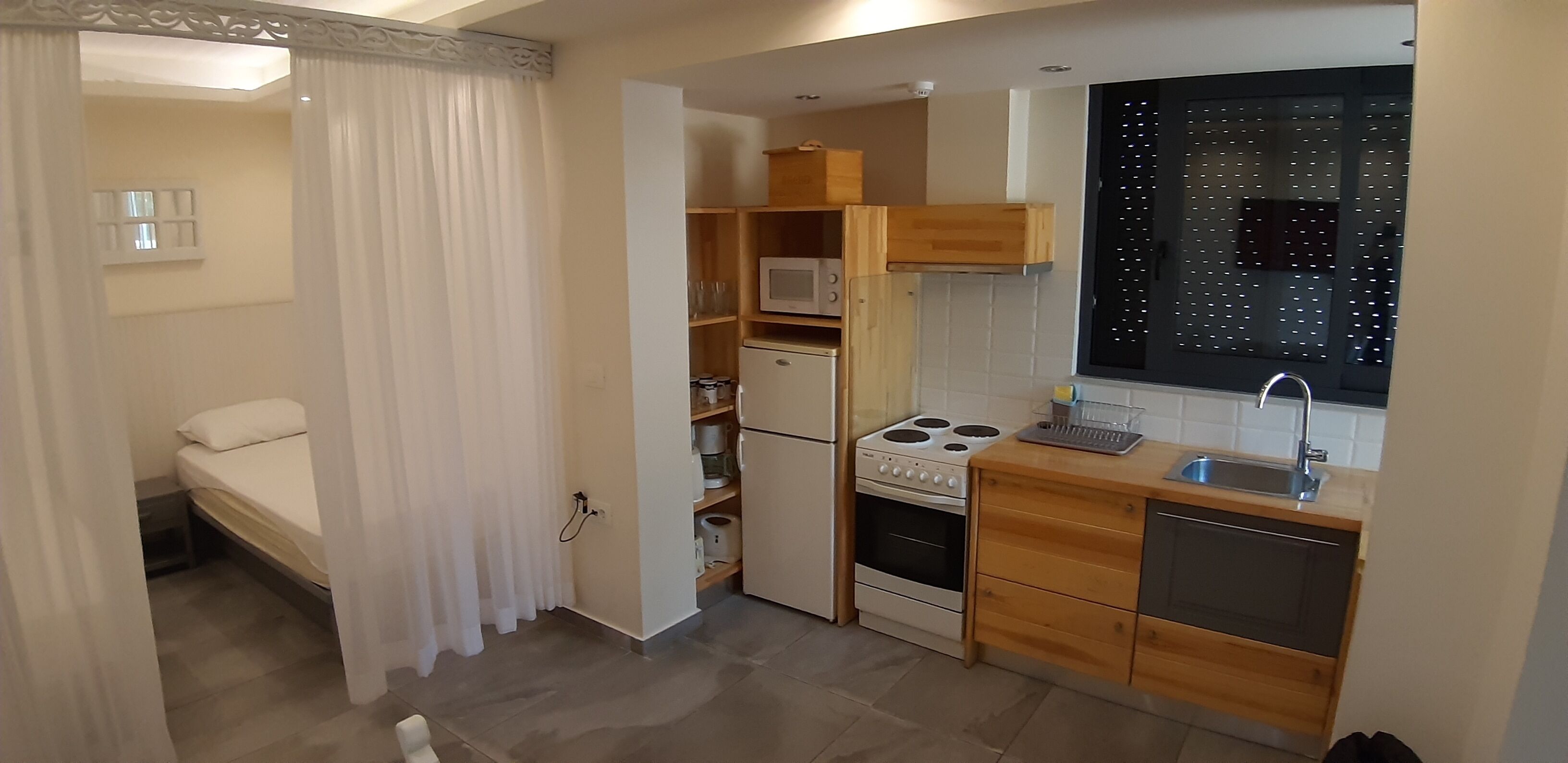 A compact kitchen with a stove, microwave, and wooden cabinets.