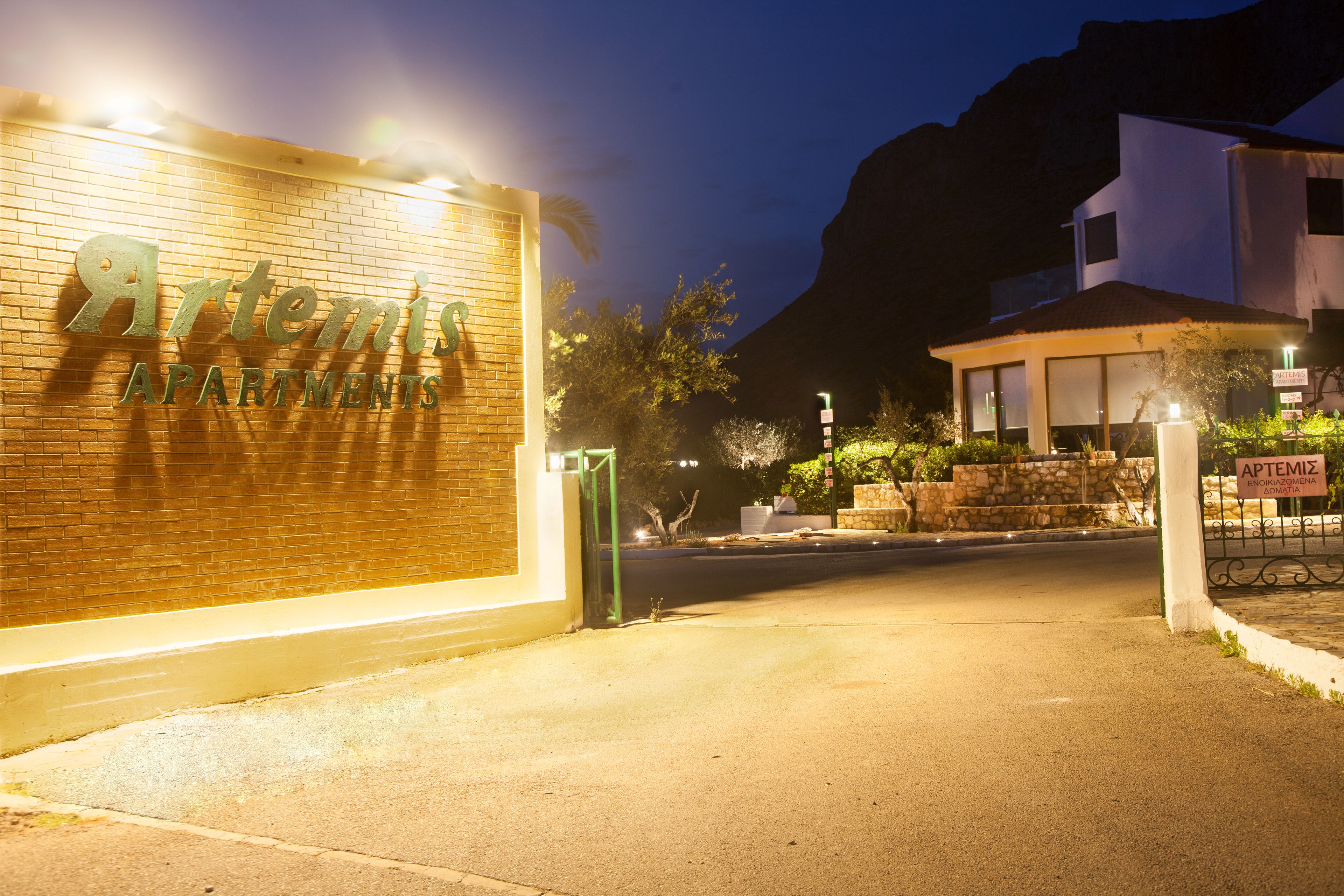 A building with a sign reading "Artemis Apartments" at night.