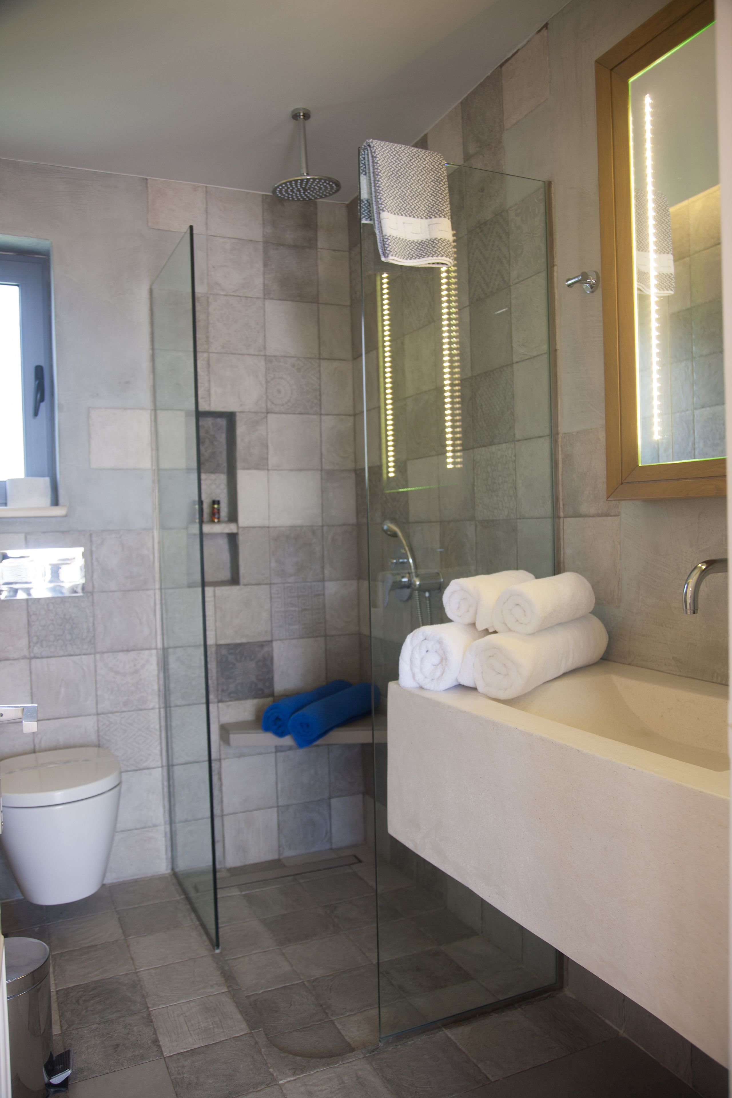 A modern bathroom with a glass-enclosed shower, a white bathtub, and neatly folded towels.