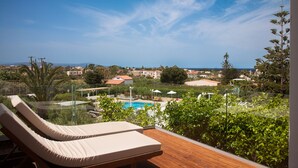 Um deque de madeira com duas cadeiras de descanso com vista para uma piscina e uma área residencial.
