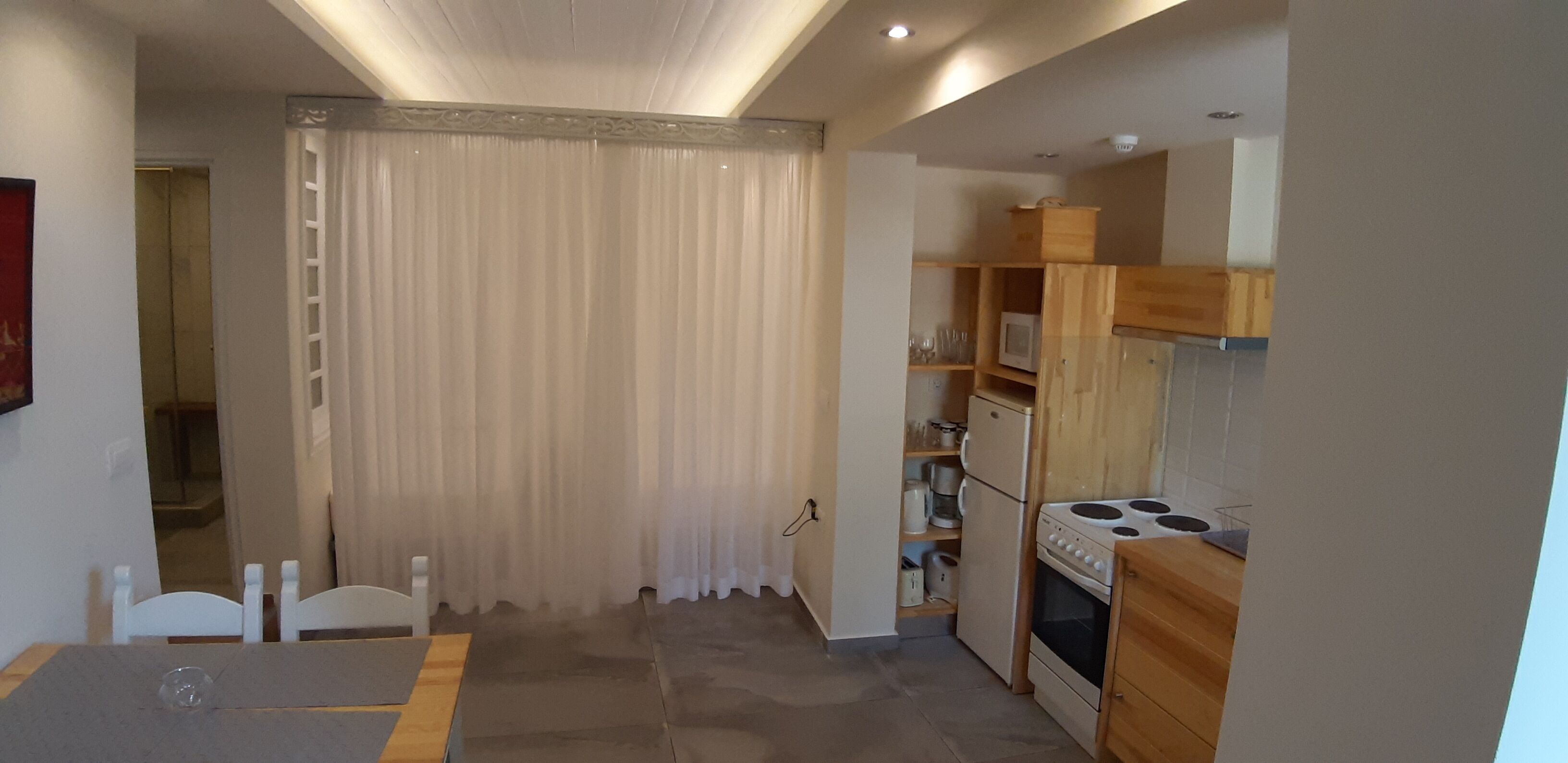 Una cocina compacta con estufa, refrigerador y estanterías de madera.