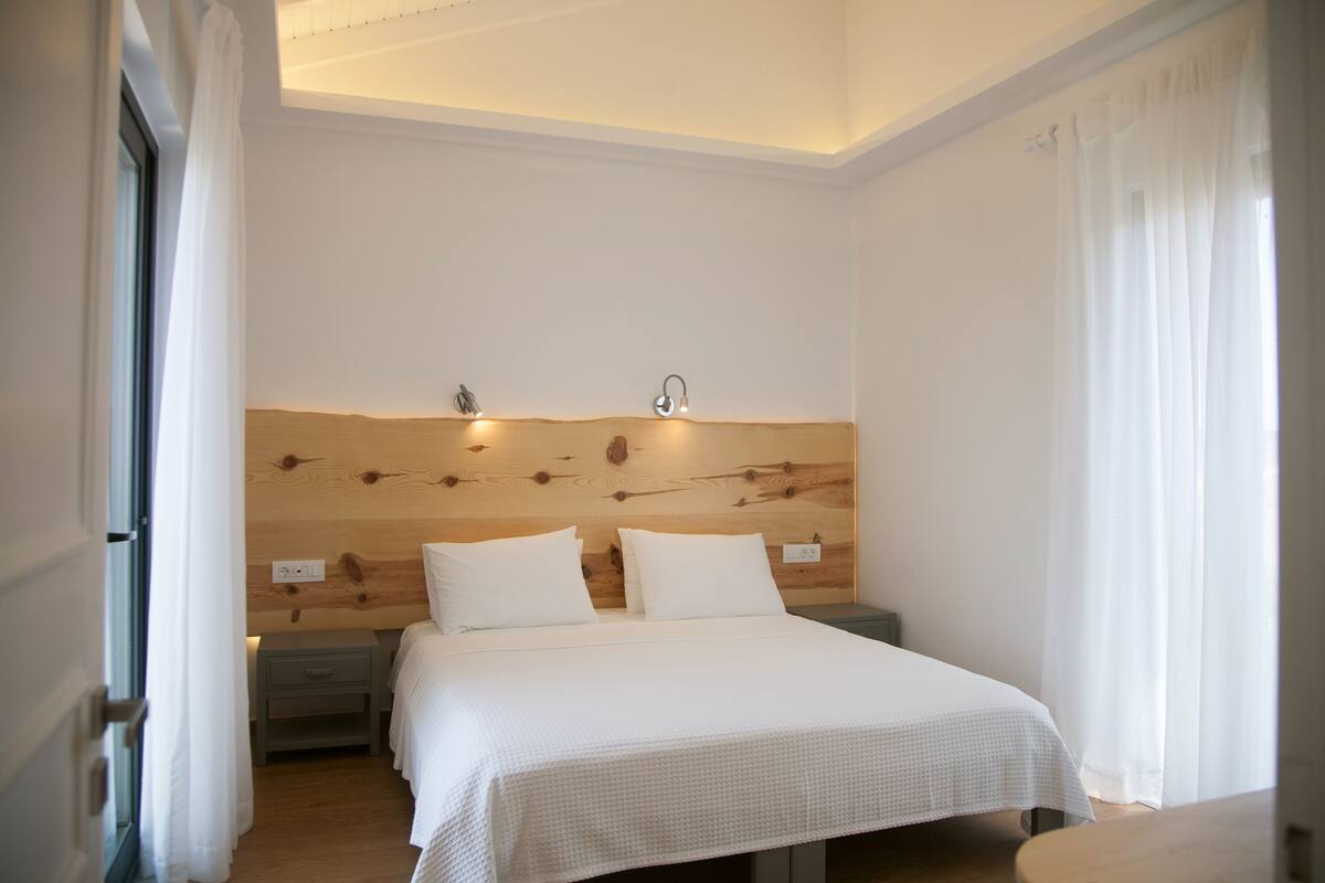 A bedroom with a wooden headboard, two bedside tables, and a bed with white bedding.