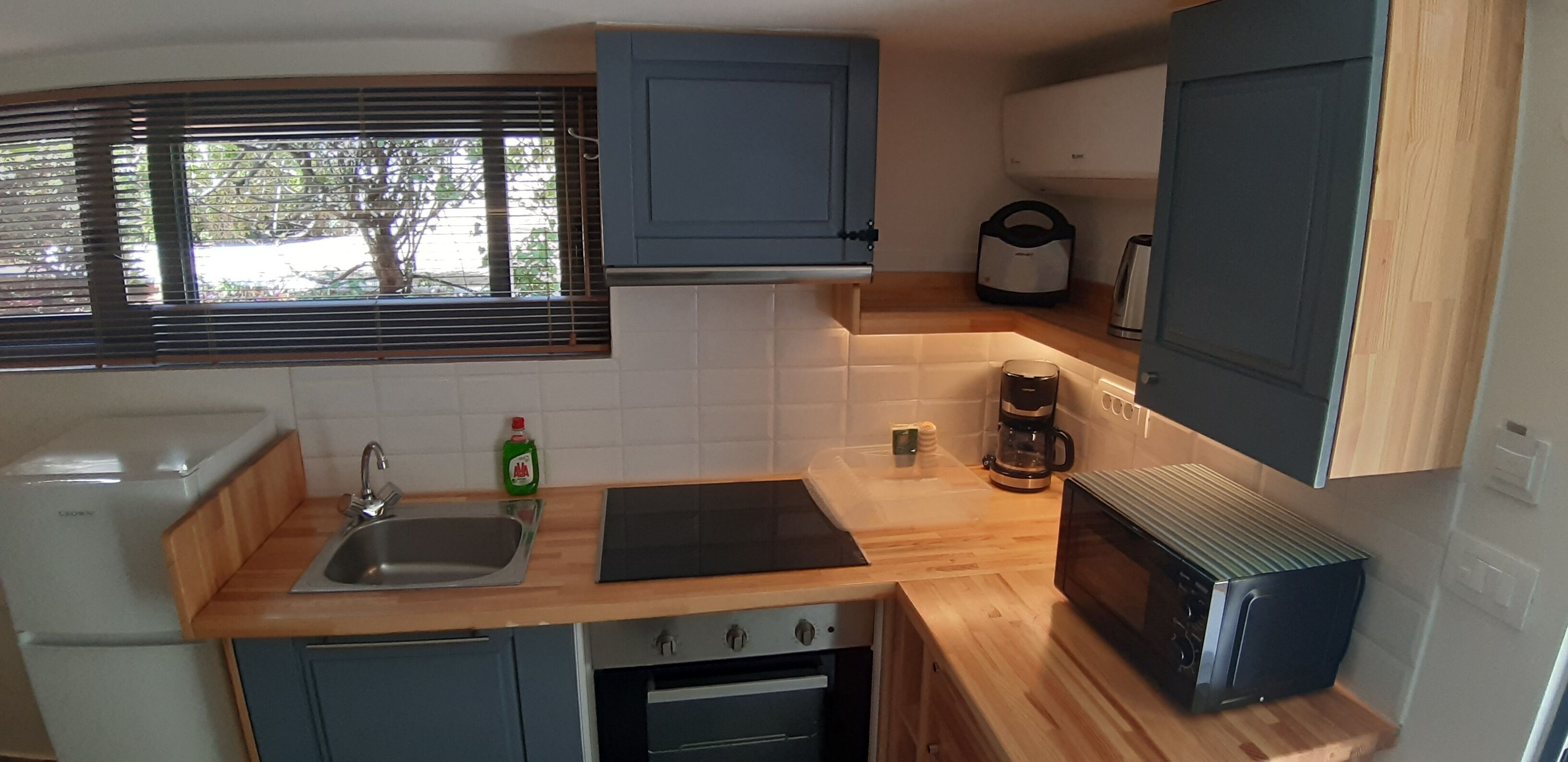 Una cocina compacta con un fregadero, microondas, cafetera y horno pequeño.