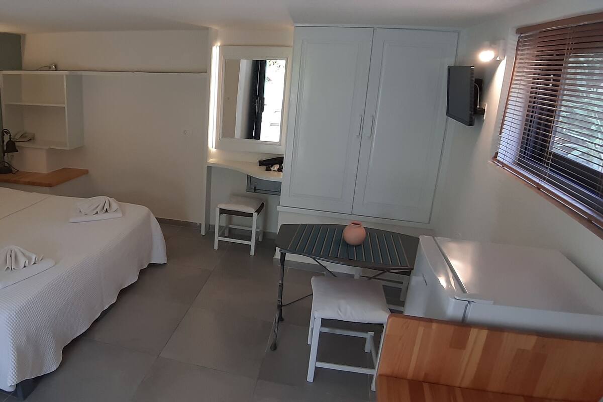 A bedroom with a bed, bedside table, and a desk with a chair.