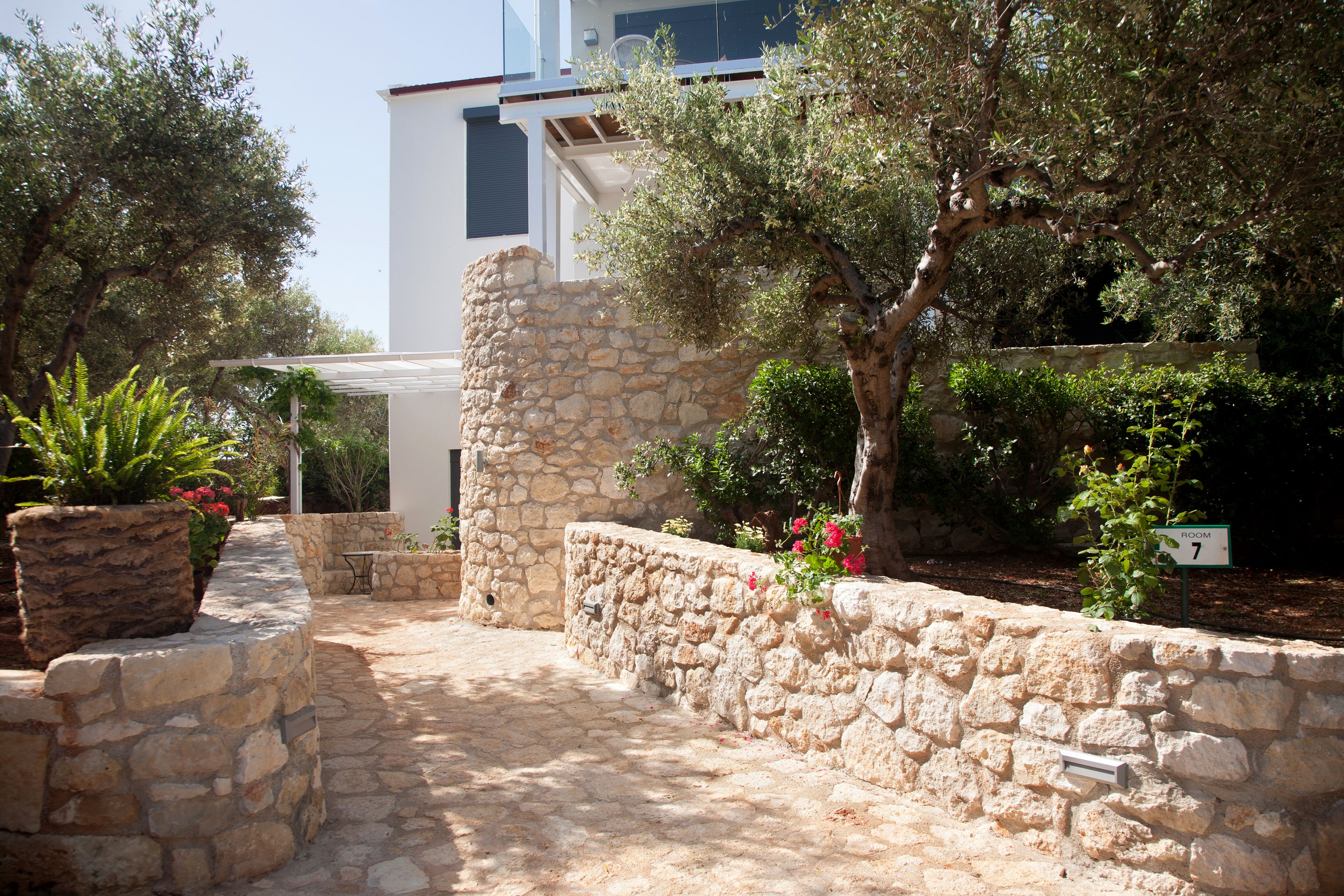 A stone pathway leading to a building with a stone wall and a sign indicating room 7.