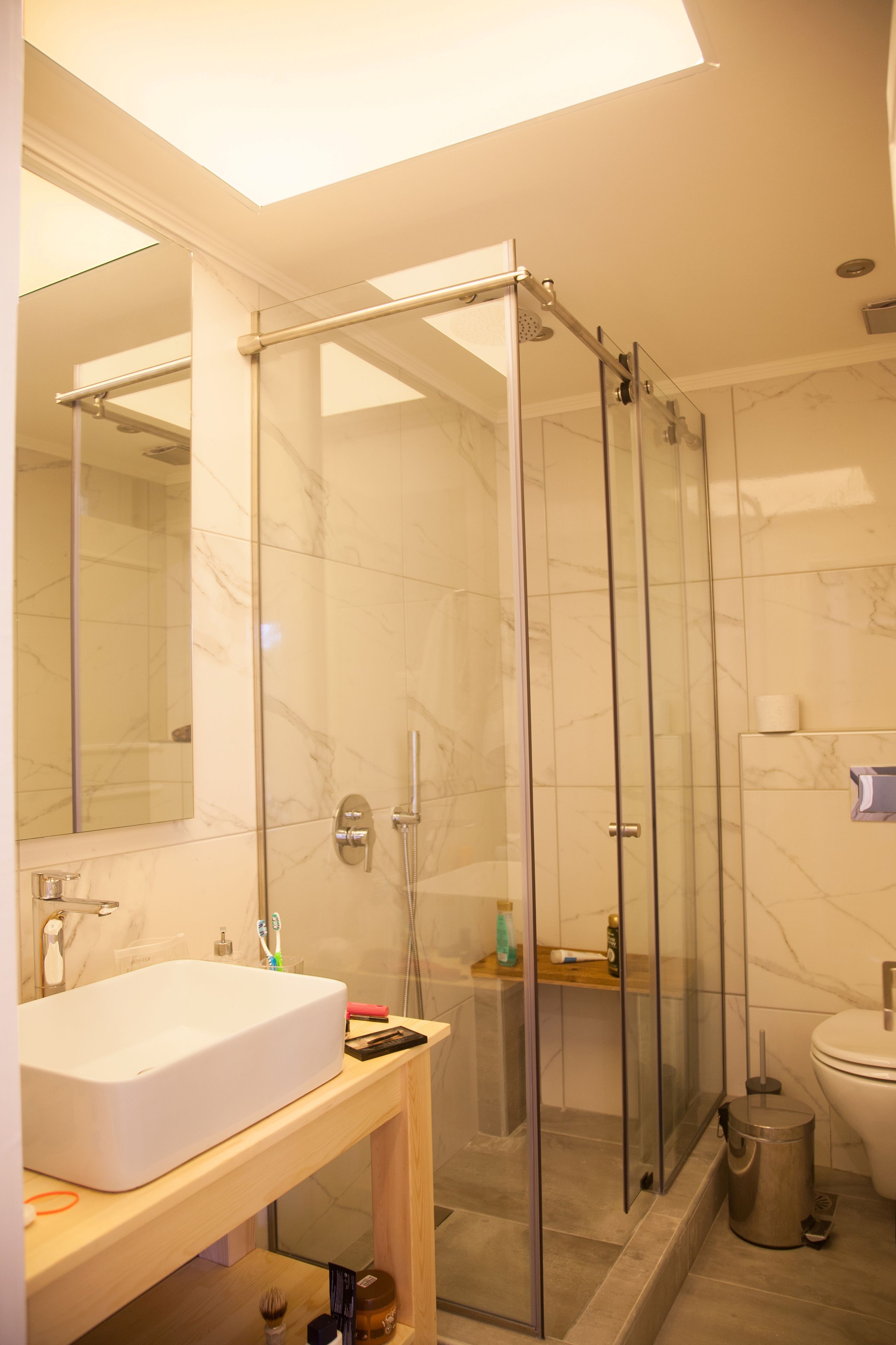Un baño moderno con ducha acristalada, lavamanos blanco y retrete.