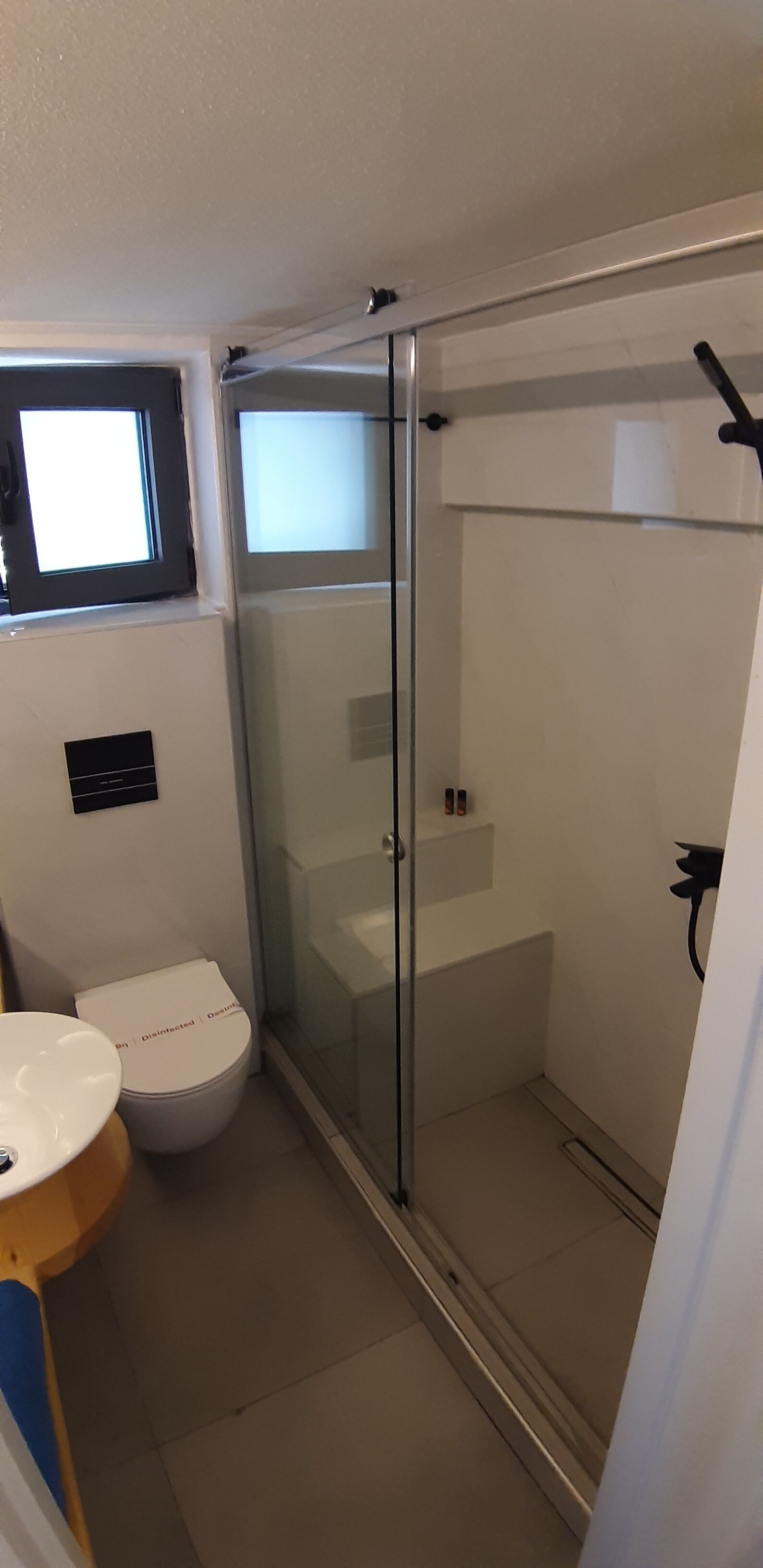 A small bathroom with a toilet, a sink, and a glass-enclosed shower area.