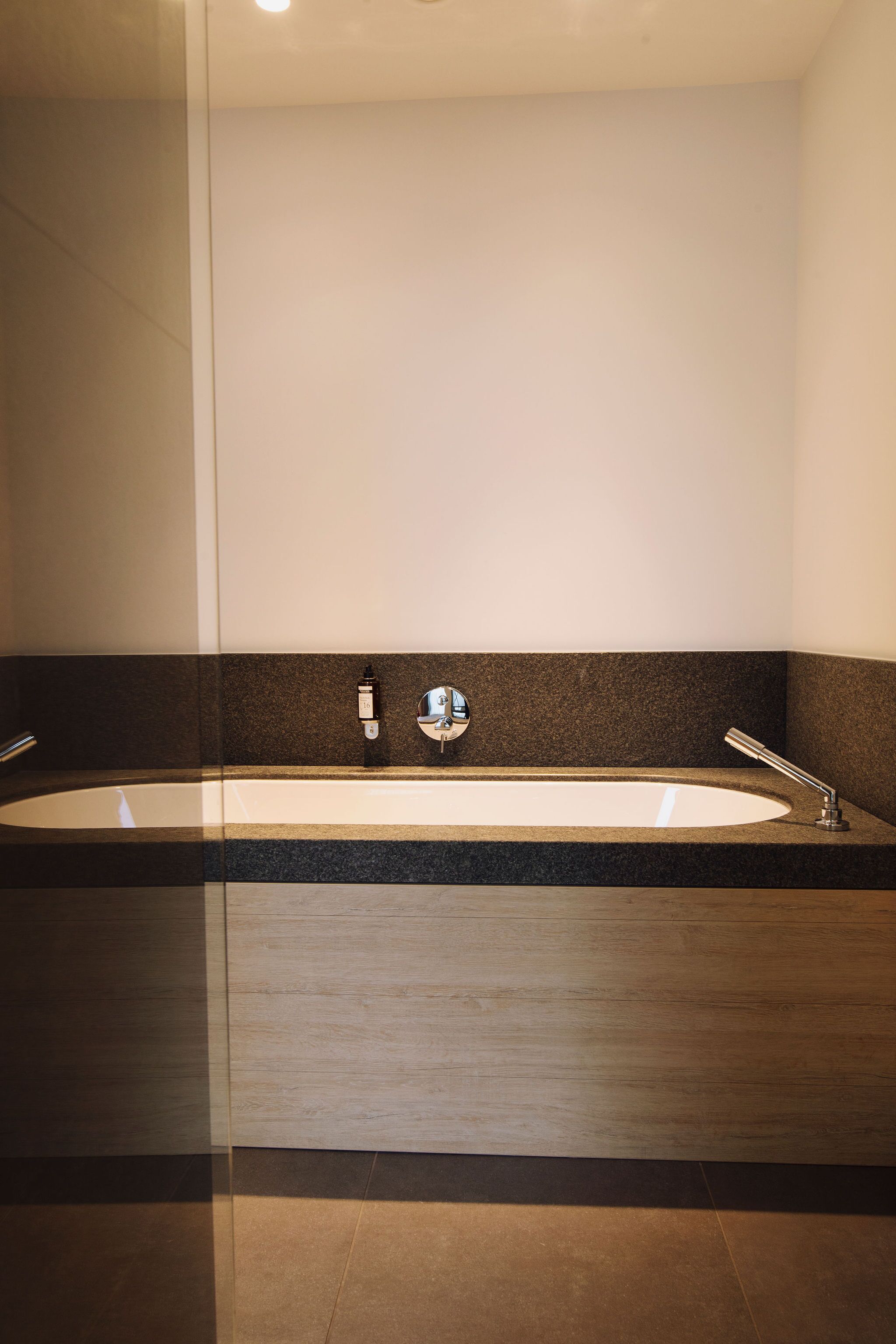 Un baño moderno con una bañera grande, un espejo y una encimera oscura.