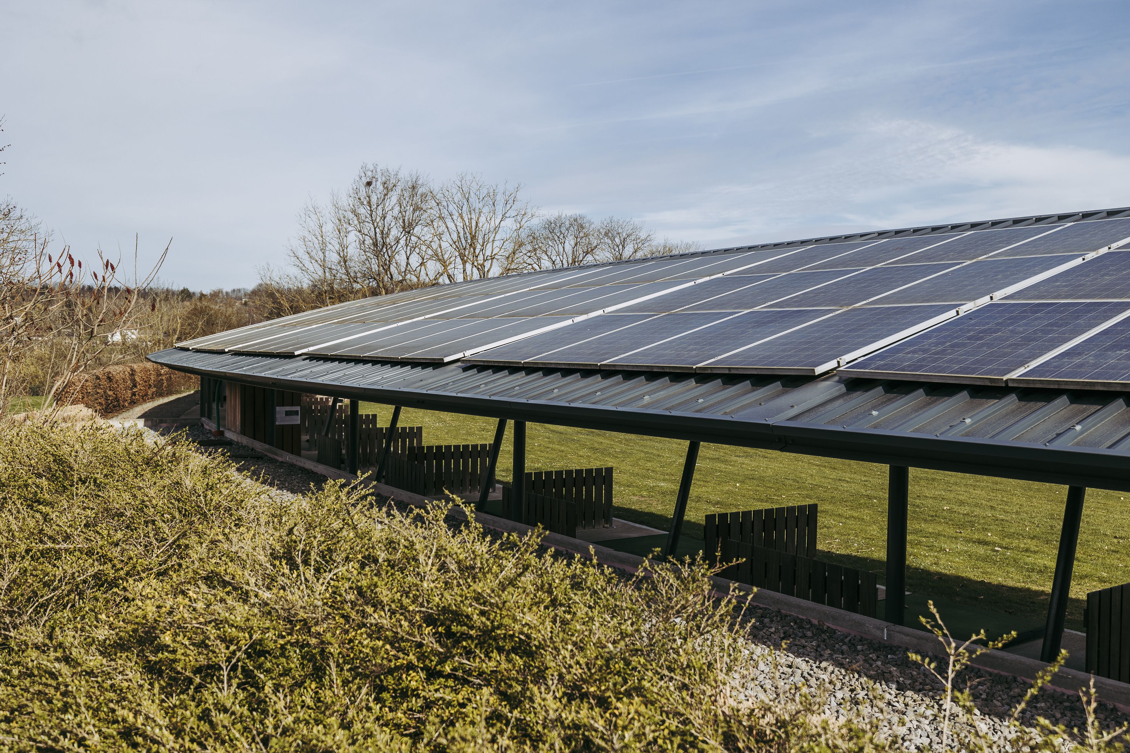 A solar panel array on a building with a covered outdoor area and seating.