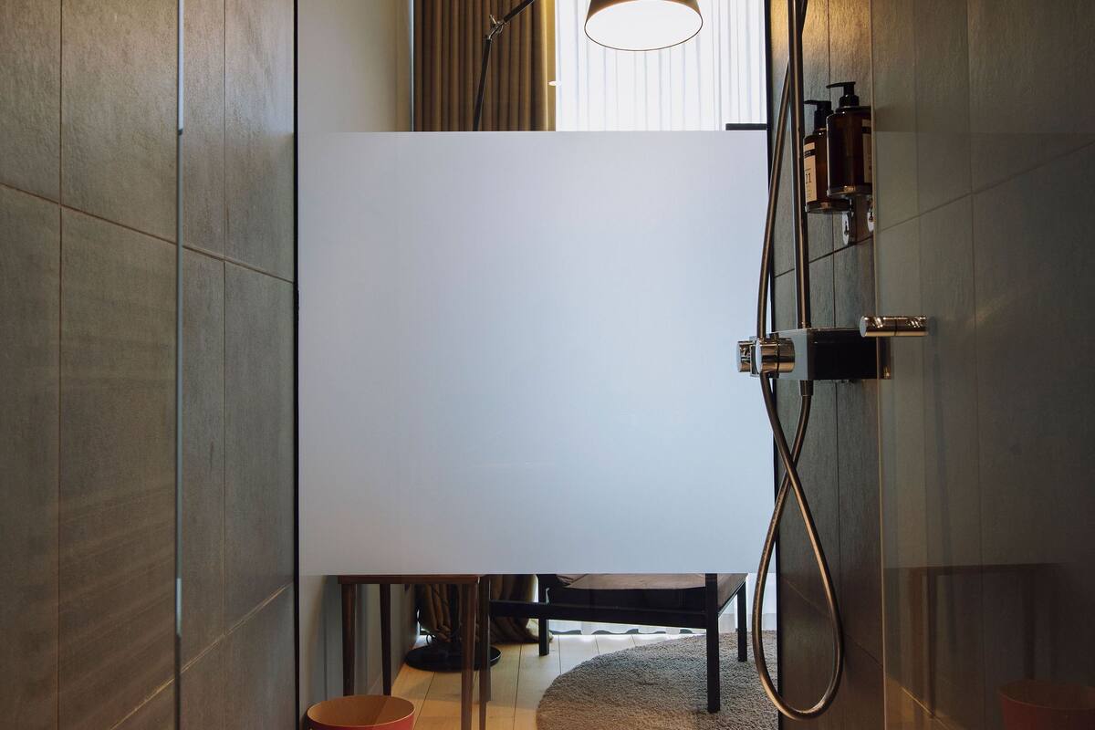 A modern bathroom with a shower, a towel rack, and a mirror.