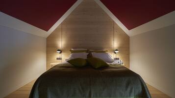 Un dormitorio con techo inclinado, paredes de madera y una cama con colcha verde a cuadros.