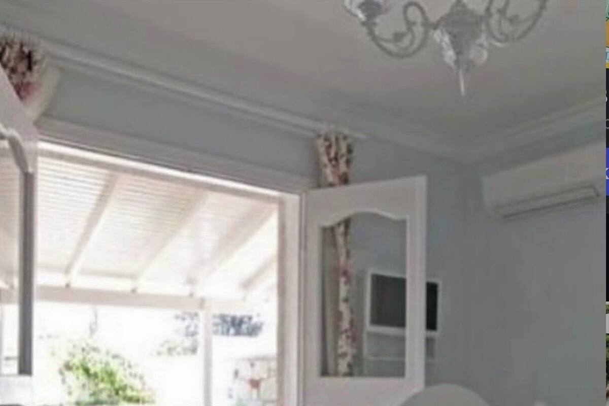 A bedroom with a bed, a mirror, and a door leading to an outdoor area.