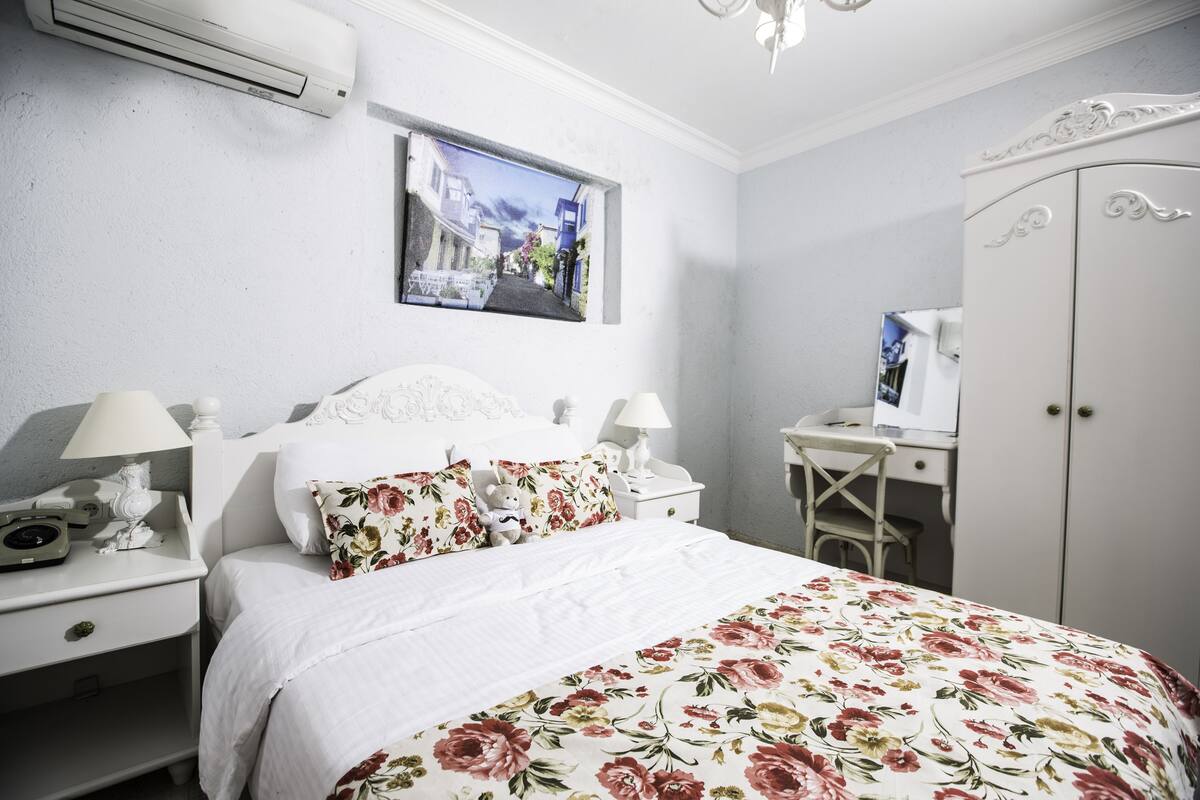 A neatly arranged bedroom with a bed, a desk, and a wardrobe.