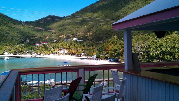 A balcony with chairs overlooking a beach and water. - Sea Crest Inn (Jost Van Dyke)