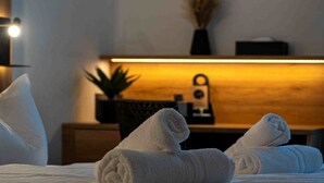 Une chambre d’hôtel avec un lit bien fait, une table de chevet avec une lampe et une petite plante en pot posée sur la table de chevet.