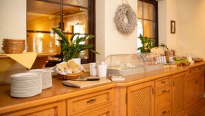 Un buffet avec du pain, des assiettes et un saladier de fruits.
