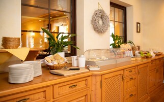 Disposição de buffet com pão, pratos e uma cesta de frutas.