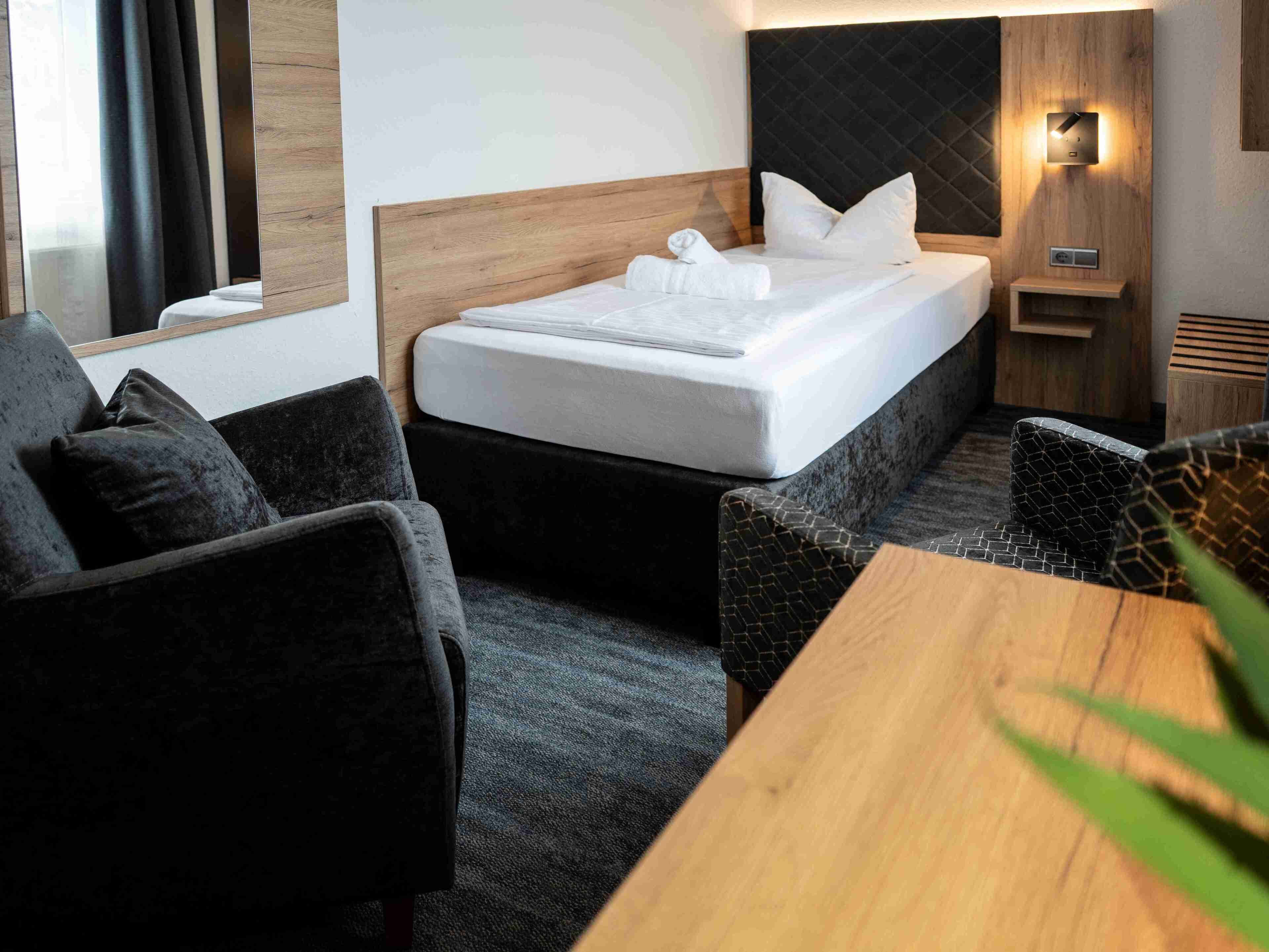 Una habitación de hotel con una cama, una mesita de noche, una silla y una pequeña mesa.