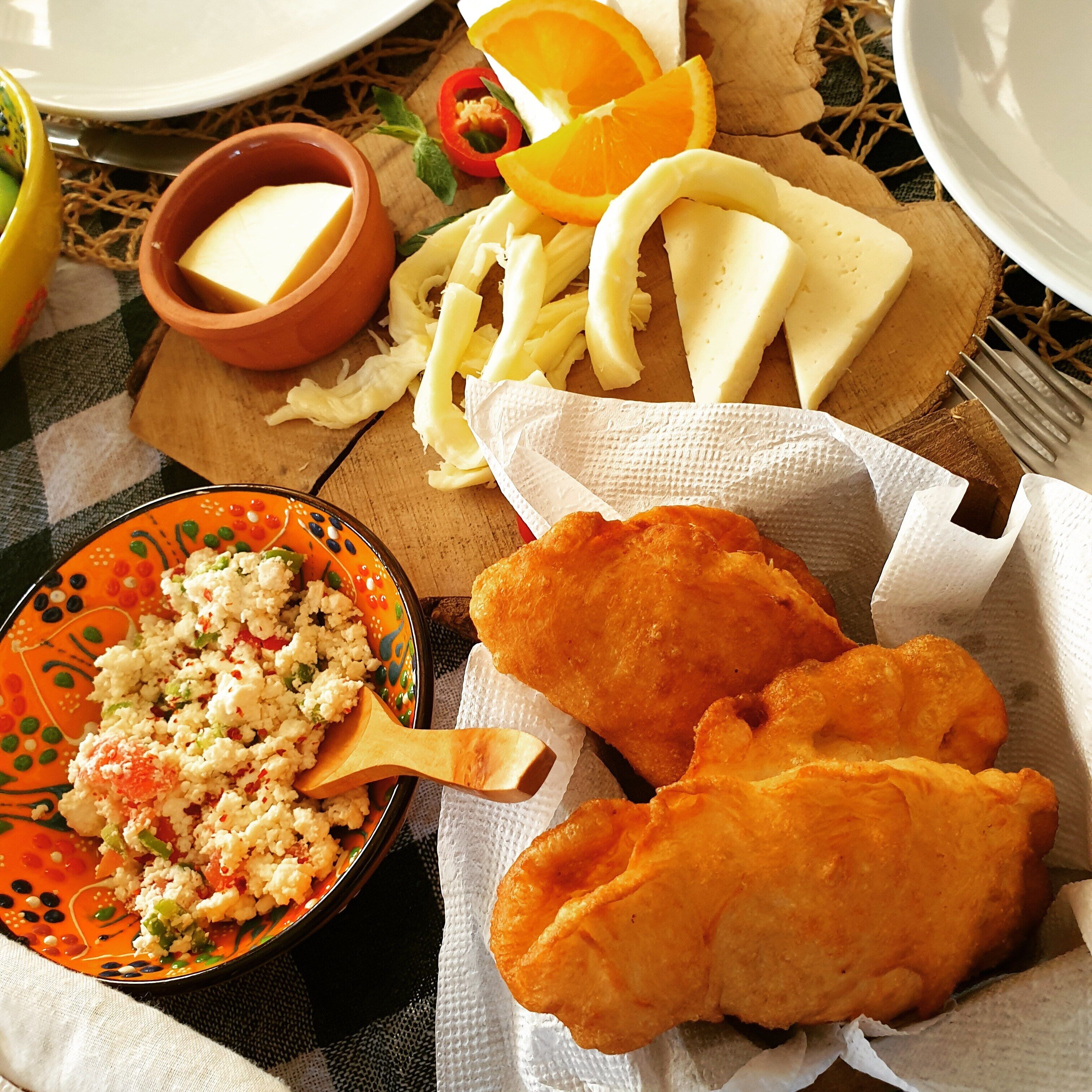 Een tafel met verschillende soorten eten, waaronder een saladeschaal, kaas en brood.