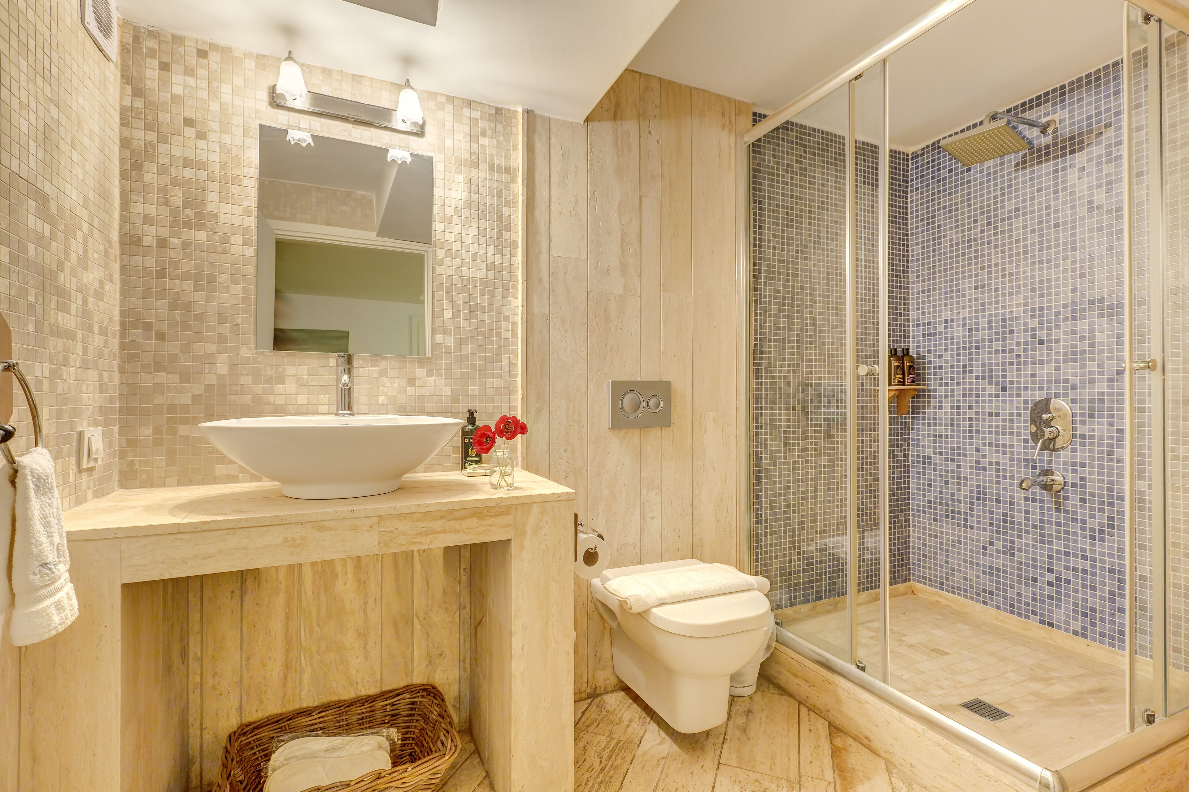 A bathroom with a large sink, toilet, and glass-enclosed shower.
