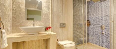 A bathroom with a large sink, toilet, and glass-enclosed shower.