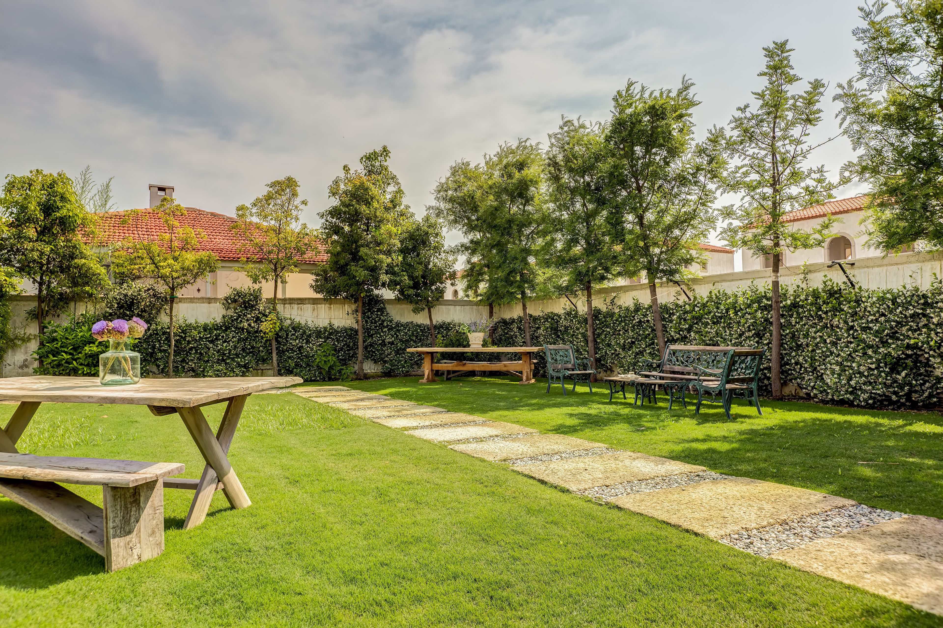 Ein gepflegter Garten mit einem Holztisch, Bänken und einem Kiesweg.