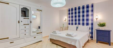 A bedroom with a bed, bedside table, nightstand, wardrobe, and a patterned rug.
