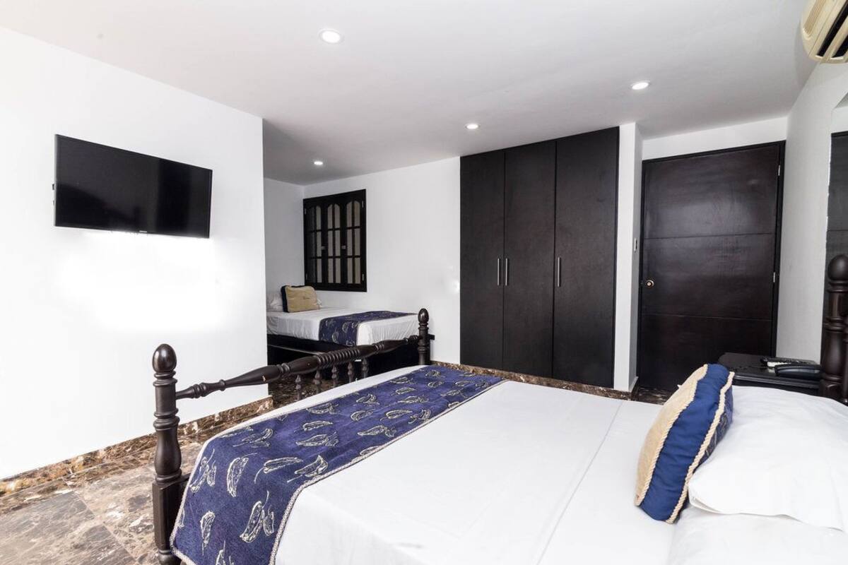 Une chambre à coucher avec un lit, un téléviseur fixé au mur et une armoire.