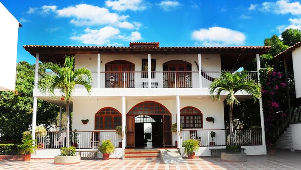A two-story building with a balcony, arched windows, and a tiled entrance.