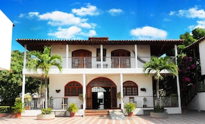 Un edificio de dos pisos con balcón, ventanas en arco y entrada con azulejos.