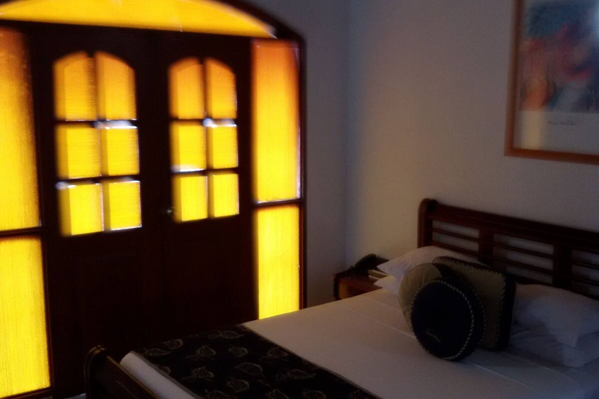 Une chambre avec un lit, une table de chevet et un tableau accroché au mur.
