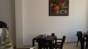 Un comedor con una mesa y sillas, un cuadro en la pared y una máquina de café.