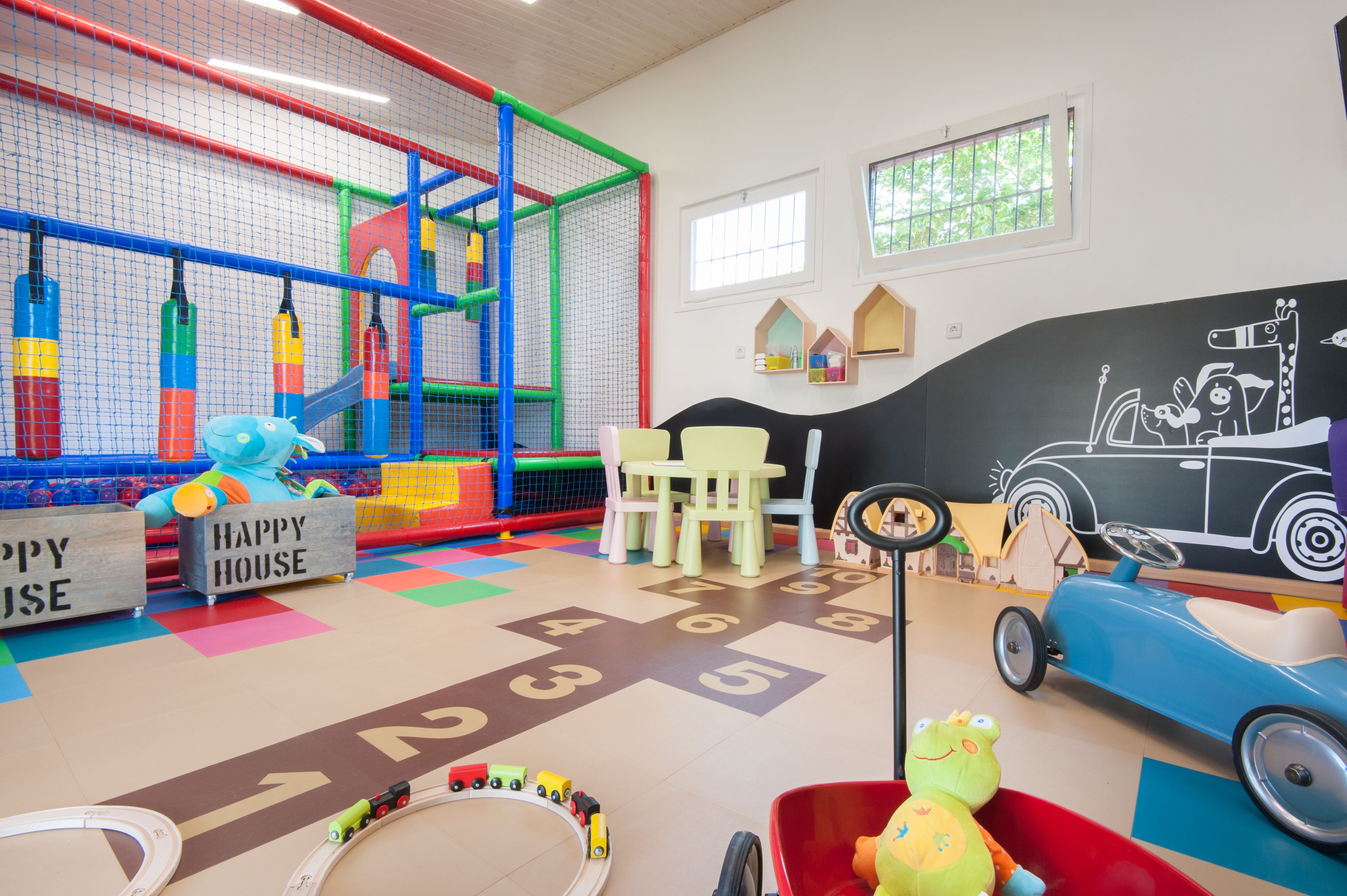 Een kinderspeelplaats met een kleurrijke speelconstructie, een speelgoedauto en een knuffelfros.