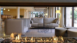 A modern lounge area with a fireplace, sofas, and a dining area. - Hotel Mas Solà (Santa Coloma de Farners)