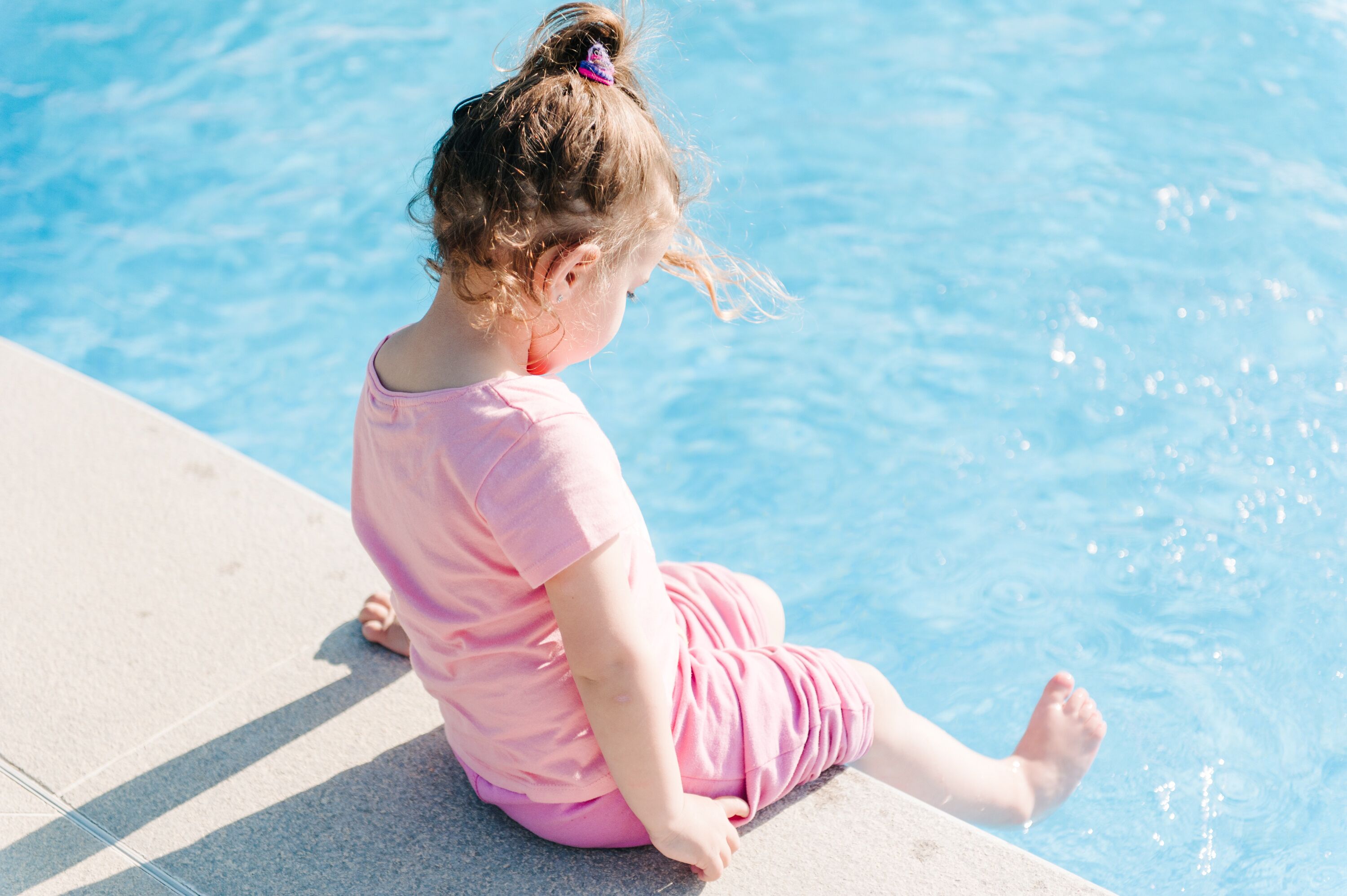 Un niño sentado junto a la piscina.