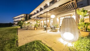 A well-lit outdoor patio area with seating and potted plants. - Hotel Mas Solà (Santa Coloma de Farners)