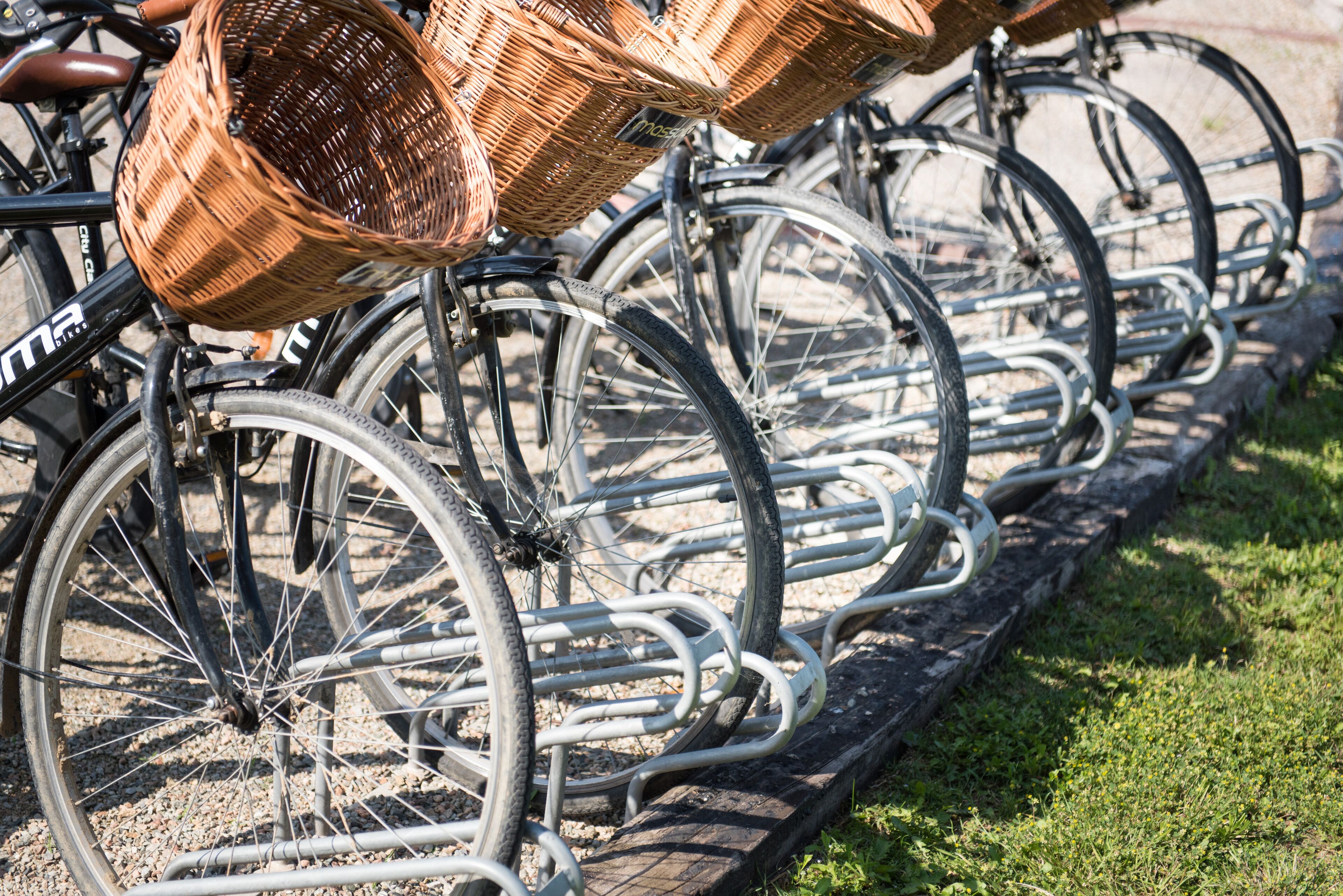 Une rangée de vélos équipés de paniers, garés sur un porte-vélos.