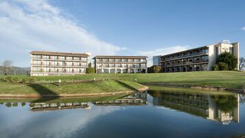Un hôtel avec un bassin d’eau aux reflets changeants, des bâtiments modernes et un ciel dégagé.