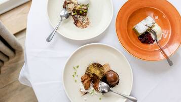 Three plates of dessert on a white tablecloth.